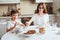 Kid brother and teen sister having breakfast at home in modern white kitchen and eating snacks