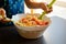 Kid cooking mediterranean salad with beans corn and cherry tomatoes