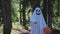 kid in a costume ghost with orange balloon. Halloween celebration holiday. Funny smiling grimace