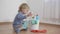 Kid in danger sitting near a bucket with plastic bottles with household chemicals, little boy sprays glass detergent on