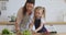 Kid daughter learning cooking helping mom cut vegetable salad