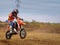 Kid doing wheelie on his motorcycle on dirt track