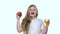 Kid drinks juice from a glass and holds an apple. White background. Slow motion