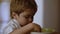 Kid eating bowl of oatmeal for breakfast. Child eating while watch cartoons