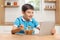 Kid eating cereals at a wooden counter and watching on a tablet