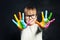 Kid enjoying his painting. Cute child girl with colorful hands on classroom blackboard background. Arts and creative education