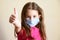 Kid in face mask for protection to corona virus shows thumb up