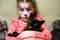 Kid with face painting of kitty, cute little girl with painted mask on her face holds cat