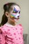 Kid with face painting of kitty, cute little girl with painted mask on her face of rainbow cat