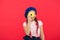 Kid fan of baked donuts. Delicious sweet donut. Girl in beret hat hold donut red background. Kid playful girl eat donut