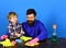 Kid with father wiping wooden table by yellow rags.