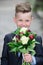 Kid with flowers bouquet. Lifestyle portrait of funny kid outdoors. Summer kids outdoor portrait. Close up face of cute