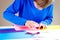 Kid folding colored paper and making origami.