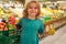 Kid with fruits. Kid choosing fruits and vegetables during shopping at vegetable supermarket. Little kid going shopping