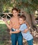 Kid girl and boy embracing and showing V gest outdoor