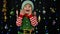 Kid girl in Christmas elf Santa Claus helper costume. Child doing winner gesture, wawing hands