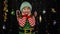 Kid girl in Christmas elf Santa Claus helper costume laughing happily on background with garland