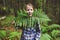 Kid girl exploring summer forest, playing with wild ferns.