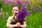 Kid girl holding a brown backpack filled with purple flowers lupins