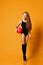Kid girl with long red hair gymnast in black swimsuit and stockings starts exercises with pink ball she holds at her hip