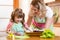 Kid girl with mom cooking fish in the kitchen