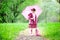 Kid girl posing outdoors with pink umbrella