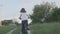 Kid girl rides a bike, girls first cycling success, sunset country road, natural landscape background, back view