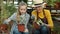 Kid girl talking to granny caring for plants enjoying gardening in greenhouse