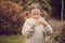 Kid girl walking in the garden in late october or november and playing with maple leaf. Children exploring nature