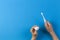 Kid hand holding electric toothbrush and putting paste from toothpaste tube over blue background