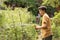 Kid hands hold hose with squirting water on the summer sunny green garden