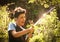 Kid hands hold hose with squirting water on the summer sunny green garden