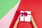 Kid hands holding present gift box with ribbon on red green and pink background. Congratulations with Christmas, mother