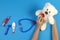 Kid hands with toy stethoscope, teddy bear and toy medicine tools on light blue background. Children doctor, medicine