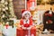 Kid having fun near Christmas tree indoors. Happy child holding a red gift box with both hands. New year kids. Merry