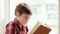 Kid holding book, smart boy flipping pages of schoolbook, child closeup portrait, kid reading book