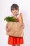 Kid holding paper grocery bag full of vegetables milk, bread. Happy child with grocery bag full of healthy food isolated on white.
