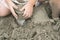 Kid holds and plays sand in the plastic cup on the beach