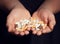 Kid holds stack of colorful pills and drugs in his palms on dark moody background