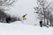 Kid jumping over a hill made of snow with snowboard 