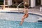 Kid jumping in swim pool. Excited child splashing water in pool. Little kid splashing in blue water of swimming pool