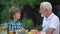 Kid laughing with grandpa telling funny stories, family having fun together