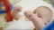 Kid lying on bed with rattle. Infant playing baby rattle.