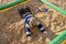 The kid is lying on his stomach in the sand in the city playground.