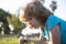 Kid with magnifying glass lying in grass. Happy smiling child boy relaxing on the grass. Cute kid boy enjoying on grass