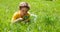 Kid on the meadow looking the grass with a magnifying glass.