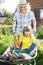 Kid and mother in domestic garden. Child sitting