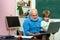 Kid with old teacher learning in class on background of blackboard - generation people concept. Portrait of grandfather