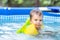 Kid in oversleeves swims in the pool in the yard