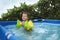 Kid in oversleeves swims in the pool in the yard